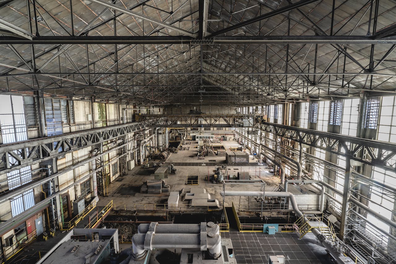 A wide-angle view of a spacious industrial warehouse interior with steel structures and machinery.